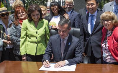 Image of Mayor Garcetti signing a document surrounded by people