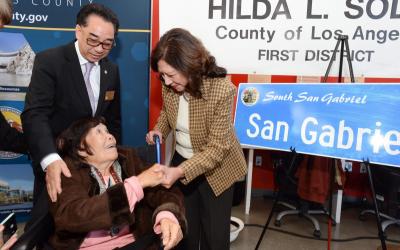 Image of elderly woman in a wheel chair shaking hands with another woman