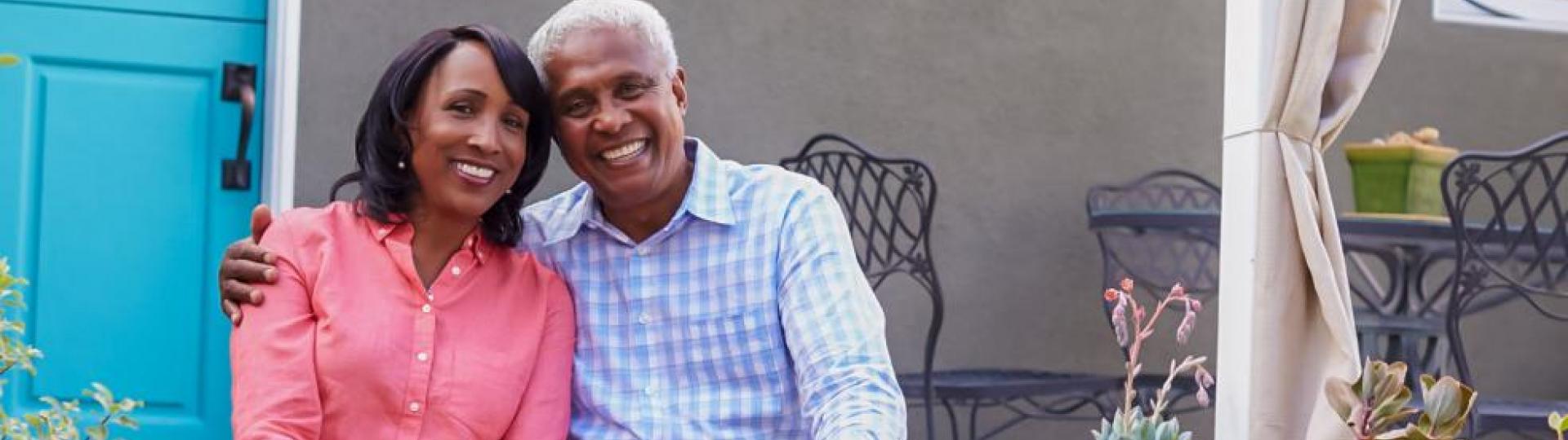 Image of a male and a female sitting in front of a house smiling