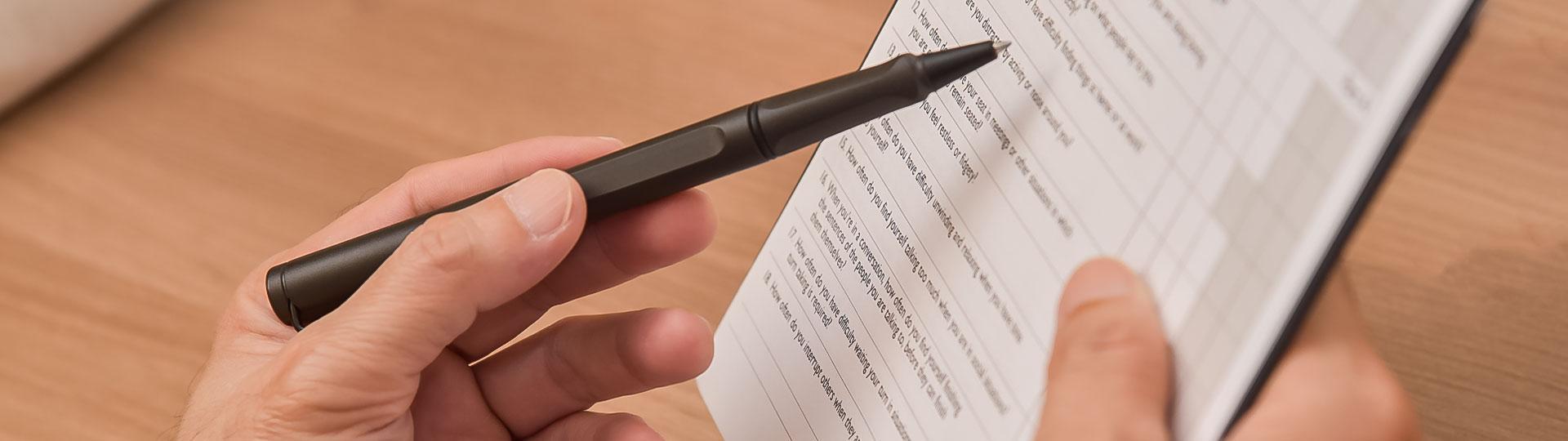 Zoomed in Image of a hand holding a pen and a clipboard