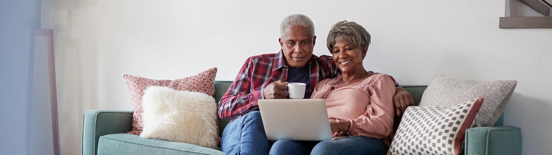Image of a senior couple sitting on the couch looking at a laptop
