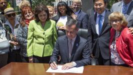 Image of Mayor Garcetti signing a document surrounded by people Image of Mayor Garcetti signing a document surrounded by people